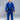 A person stands barefoot on a white floor, wearing the Lightweight BJJ Gi Blue and a black belt with red bar, against a plain gray background. They face forward with a neutral expression and hands by their sides.
