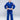 A young boy wears the Kids Competition BJJ Gi Blue, barefoot on a white floor, holding his white belt and facing the camera with a neutral expression.