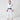 A child stands barefoot on a white background wearing the Kids Competition BJJ Gi White, featuring a black belt and red patches on the shoulders and chest. The child faces forward with a neutral expression.
